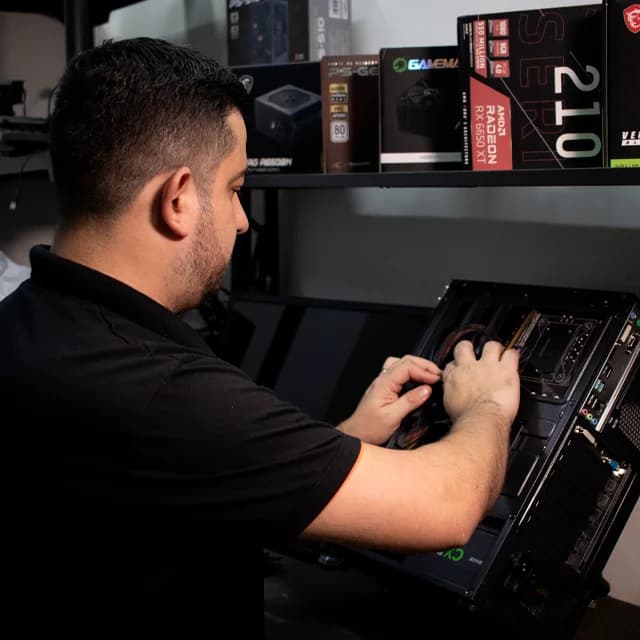 Técnico com pulseira antiestática fazendo diagnóstico na placa-mãe de um notebook aberto sobre a bancada